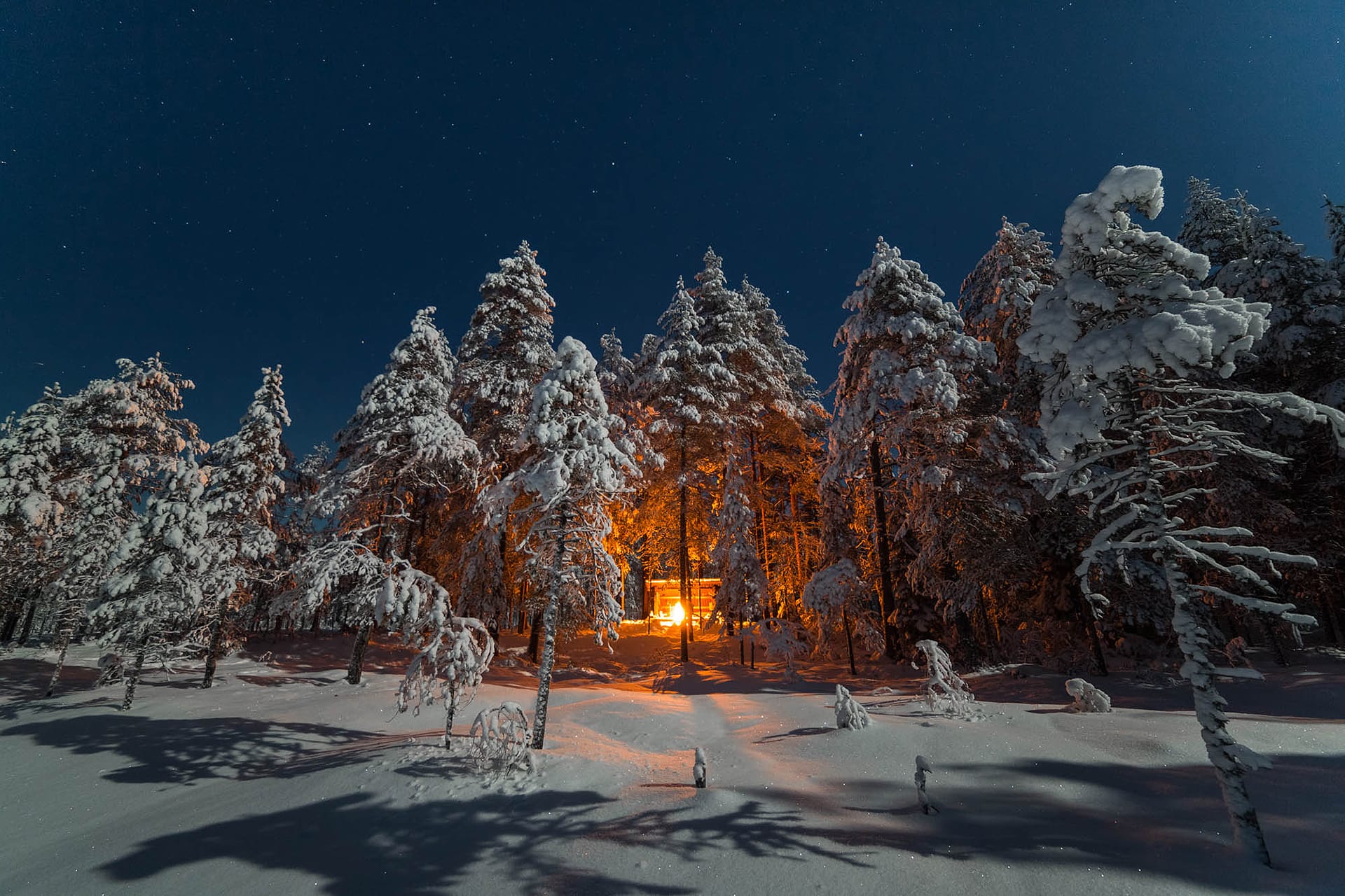 Nuotio laavulla pimeänä talviyönä, kirkas tähtitaivas loistaa.