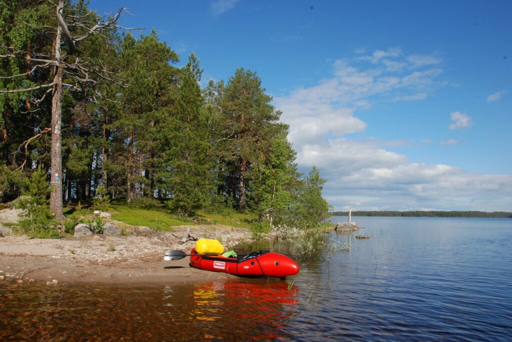 punainen packraft rannalla